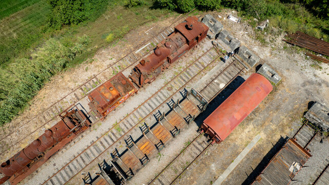 Aerial view of rusted trains and wagons resting on parallel tracks, marked by the contrasting textures of decay and the surrounding greenery, Vila Nova de Gaia, Porto District, Portugal.