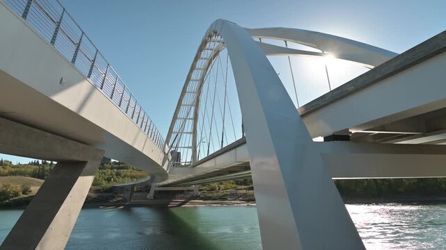 Low angle dynamic drone shot of walter dale bridge in edmonton alberta with sun flares and river view