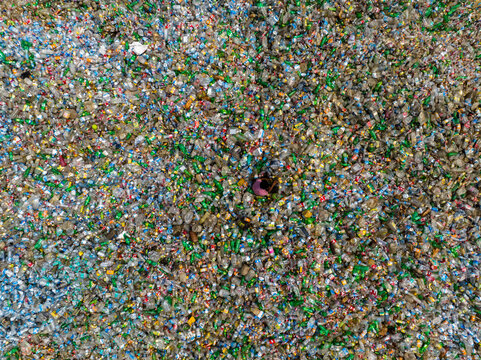 Aerial view of a vast, shimmering expanse of crushed glass, a mosaic of emerald, sapphire, and amber hues, reflecting the sun's light, Chattogram, Bangladesh.
