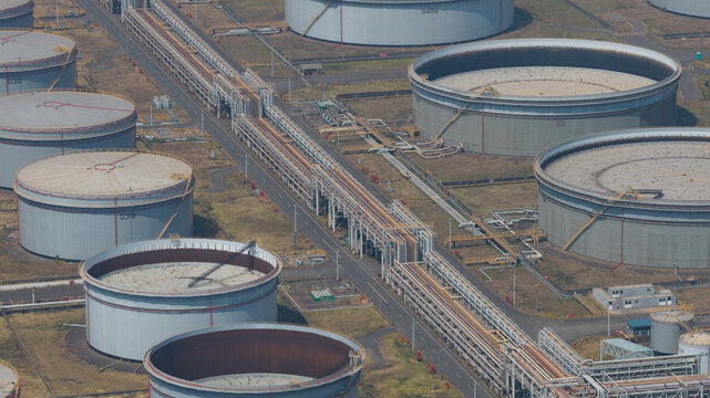 Aerial view of gleaming cylindrical tanks connected by intricate pipelines, creating a stark contrast against the industrial landscape, Dalin refinery, Kaohsiung City, Taiwan.