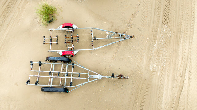 Aerial view of two boat trailers resting on the sandy beach, tire tracks surrounding them, Fort-Mahon-Plage, Hauts-de-France, France.