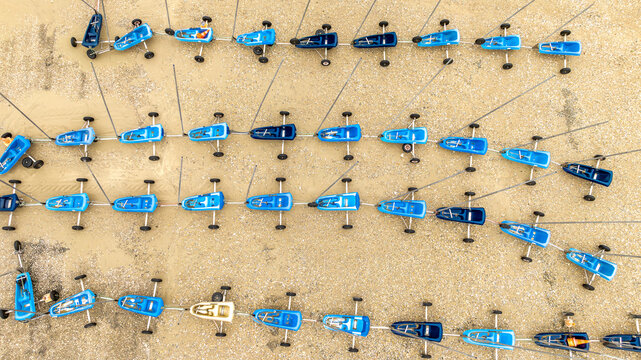 Aerial view of vibrant blue and white sand yachts lined up in neat rows, ready for a race on the sandy beach, Fort-Mahon-Plage, Hauts-de-France, France.