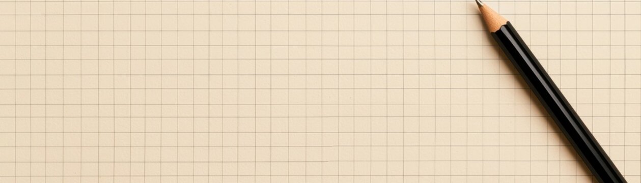 sharpened black graphite pencil rests diagonally across  beige squared paper texture