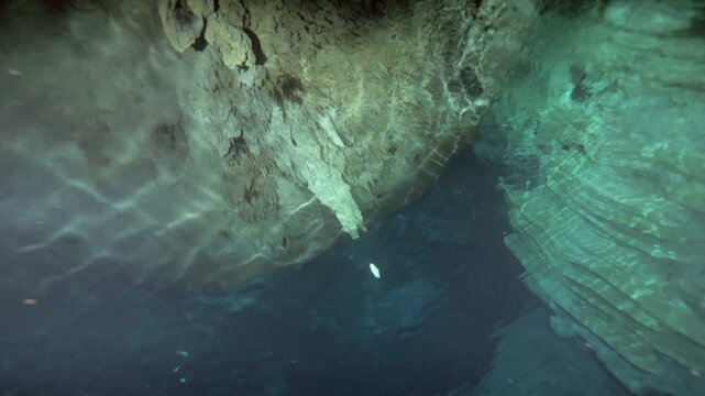 Camera looks upward from underwater toward limestone ceiling and trapped air pocket in Cenote Dos Ojos, Quintana Roo, Mexico