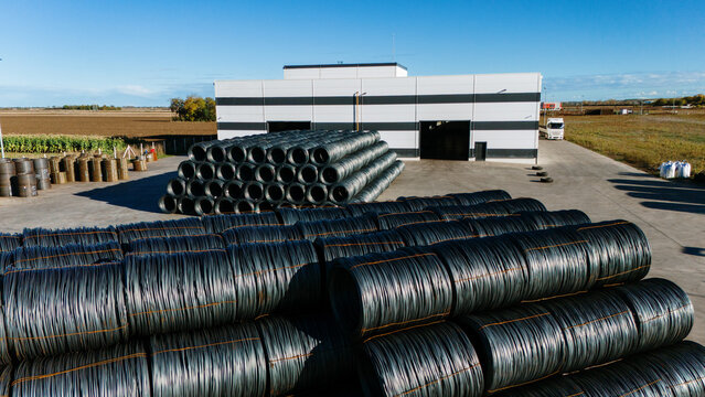 Aerial view of coils of wire neatly stacked outside a modern industrial building under a clear blue sky, Sremska Mitrovica, Vojvodina, Serbia.