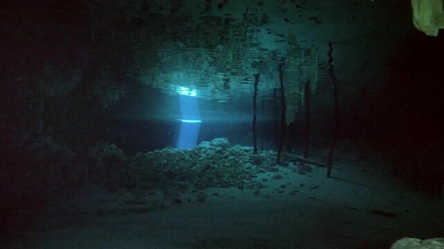 Bright light rays reflect on sandy and rocky floor creating patterns in Cenote Dos Ojos, Quintana Roo, Mexico