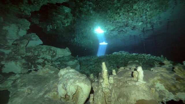Single stalagmite highlighted by reflected sun rays on cave floor in Cenote Dos Ojos, Quintana Roo, Mexico