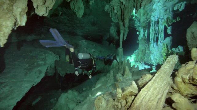 Scuba diver moves past vertical limestone column with stalactites in Cenote Dos Ojos, Quintana Roo, Mexico