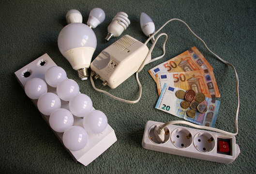 Pobreza energ&eacute;tica y factura de la luz con dinero, bombilla led y enchufe con cable, ladr&oacute;n e interruptor