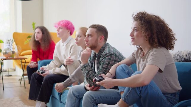 Friends in virtual reality headsets playing video games and having fun. Attractive people Resting at Home playing Games. Group of Friends having home Party sitting on couch with Snacks and Drinks.