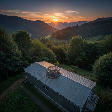 Aerial view of rural house with circular rooftop structure in lush green mountain valley at sunset