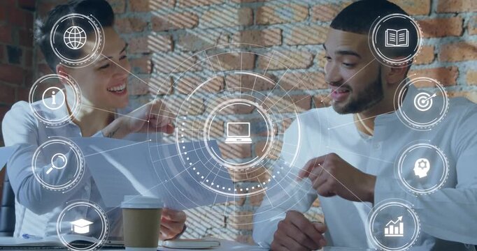 Animation of multiple digital icons against diverse man and woman fist bumping each other at office