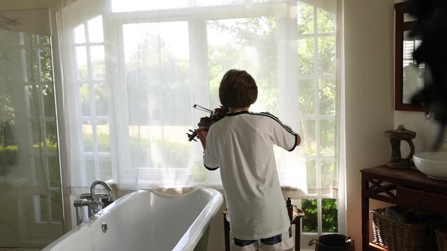 12 year old boy playing violin in bathroom