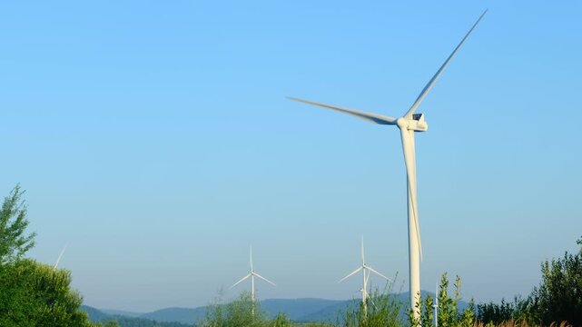 Wind generators installed at highland industrial farm against clear sky. Alternative technology of electric power generation from renewable sources
