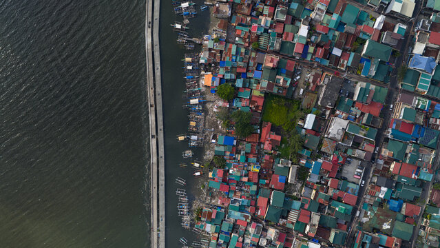 Aerial view of densely packed colorful houses and traditional fishing boats along the coast in Navotas, Metro Manila, Philippines.