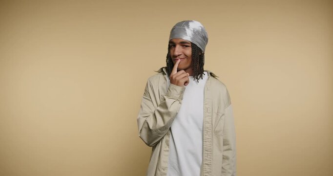 Cool guy shows fun expressions and playful gestures in a warm studio setting during a sunny afternoon
