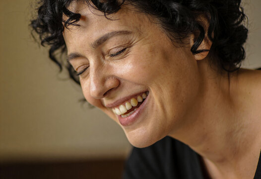 Portr&auml;t einer gl&uuml;cklichen Frau mittleren Alters mit lockigem Haar beim herzlichen Lachen
