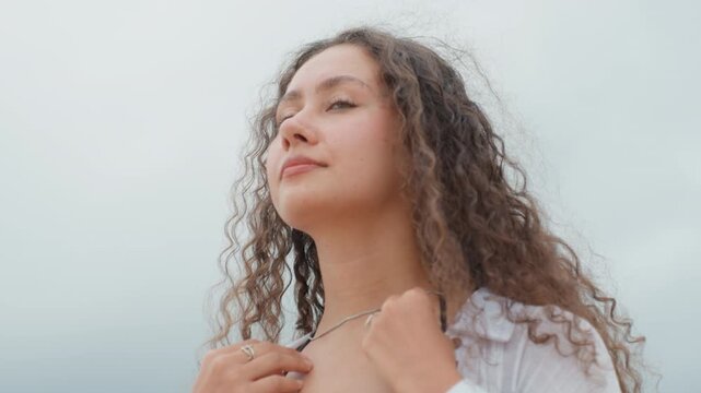 Woman gazes at ocean calmness. Female thinker peacefully admiring expansive natural landscape views. Youthful woman in serene surroundings quietly reflecting along peaceful seaside shoreline