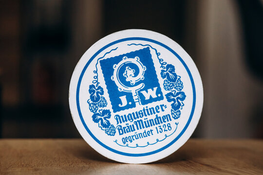 Nice, France - May 8, 2025: Augustiner Brau Munchen beer coaster with blue vintage brewery logo and traditional Bavarian design on round cardboard beer mat in close-up