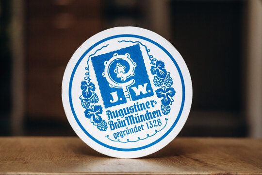 Nice, France - May 8, 2025: Augustiner Brau Munchen beer coaster with blue vintage brewery logo and traditional Bavarian design on round cardboard beer mat in close-up