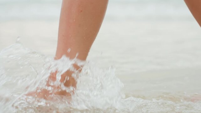 Relaxed stroll along sunny shoreline with splashing water. Calm summer day on beach with reflecting sunlight and soft surf. Unhurried barefoot walk on sandy coast as gentle waves kiss ankles