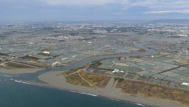 Aerial view of the winding Agongdian River flowing through vast aquaculture shrimp farms near the coast in Kaohsiung City, Taiwan.