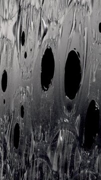 Extreme close up shot showing a sheet of plastic bubble wrap melting and disintegrating under intense heat, transforming from a solid textured surface into a viscous liquid before vanishing