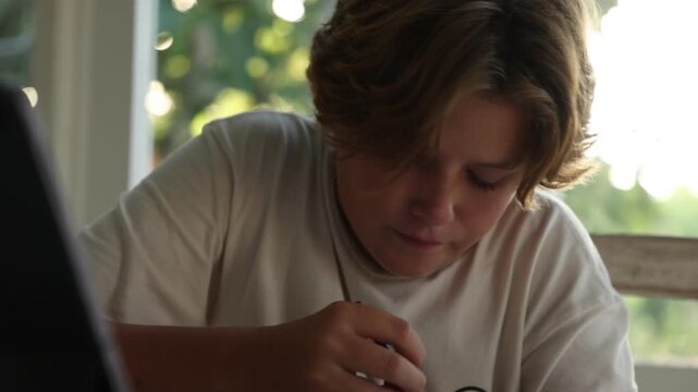 12 year old boy doing a pencil drawing in his living room