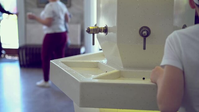 Close-up of a white marble mineral water dispenser with metal taps in a professional spa pump room.