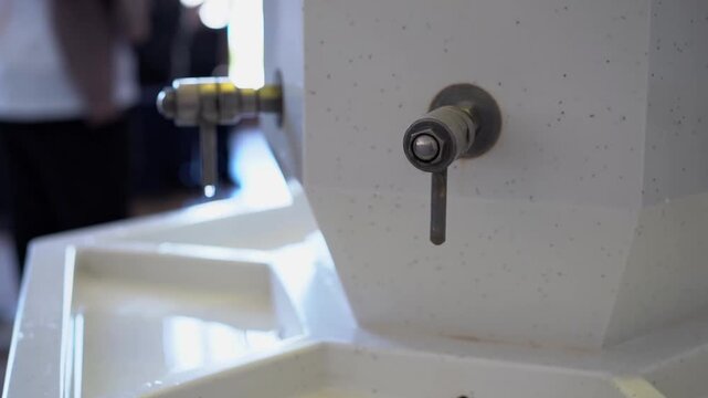 Close-up of a white marble mineral water dispenser with metal taps in a professional spa pump room.