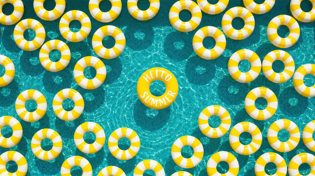 Hello Summer! Summer vacation, holiday, summertime, travel, tourism concept. A top-down view of yellow and white striped inflatable swim rings floating on a bright turquoise blue pool water surface.