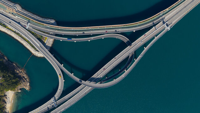 Aerial view of the Cross Bay Link bridge interchange featuring curved ramps and traffic over deep blue water in New Territories, Hong Kong.