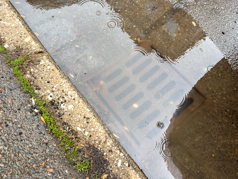 Rain water flows up out of clogged drain cover