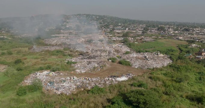 Aerial fly over view. Burning rubbish causing greenhouse gas, contributor to climate change.  Extreme Poverty. People living alongside dumpsite struggling to survive through waste picking.