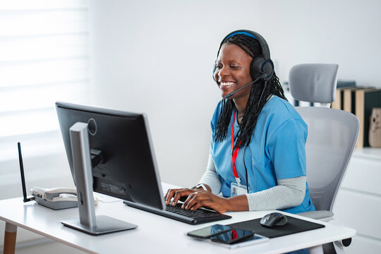 Healthcare professional wearing headset typing on computer