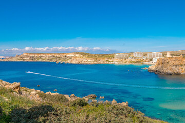 Obraz premium Clay Cliffs in Malta on a sunny day, featuring striking reddish rock formations, rugged coastline, and the deep blue Mediterranean Sea creating a dramatic and scenic landscape.