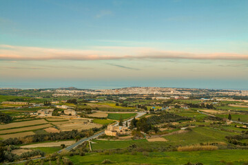 Fototapeta premium View from the Mdina fortifications in Malta overlooking the surrounding landscape at sunset, with golden light, distant views, and a peaceful panoramic scene from the scenic viewpoint.