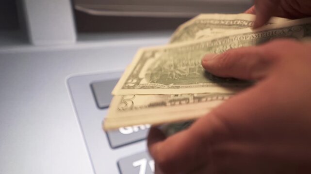A man withdraws dollar cash from an ATM.