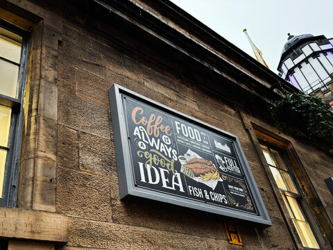 Coffee and fish and chips chalkboard sign on a sandstone restaurant facade in Edinburgh, Scotland, UK showcasing cafe food and vintage advertising