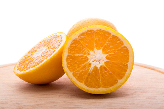 Close-up of three halved oranges on a wooden chopping board