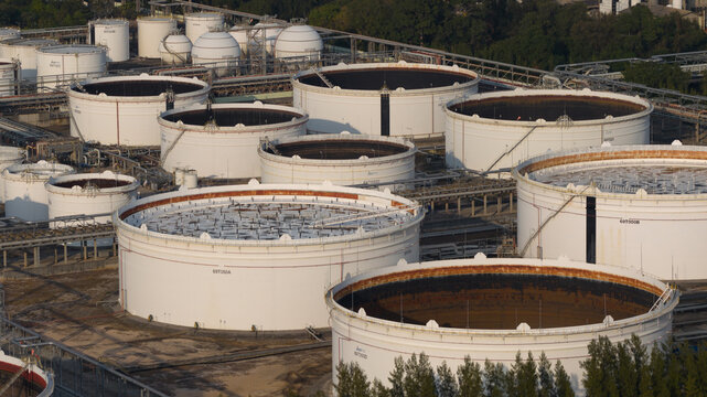Aerial view of large white storage tanks at the Map Ta Phut Industrial Estate with industrial infrastructure and surrounding greenery in Map Ta Phut, Rayong, Thailand.