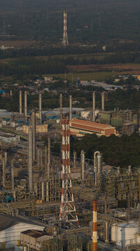 Aerial view of Map Ta Phut Industrial Estate featuring tall chimneys, complex piping systems, and storage tanks surrounded by lush greenery in Map Ta Phut, Rayong, Thailand.