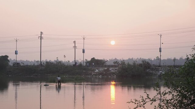 Fisherman Fishing at Sunset Golden Hour Reflection. A peaceful fisherman casting his net during sunset with golden reflections on water. Shot in January 2026, ideal for storytelling, rural life, and c