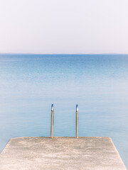 Fototapeta premium Dock extends into blue water under clear sky at the lake in midday