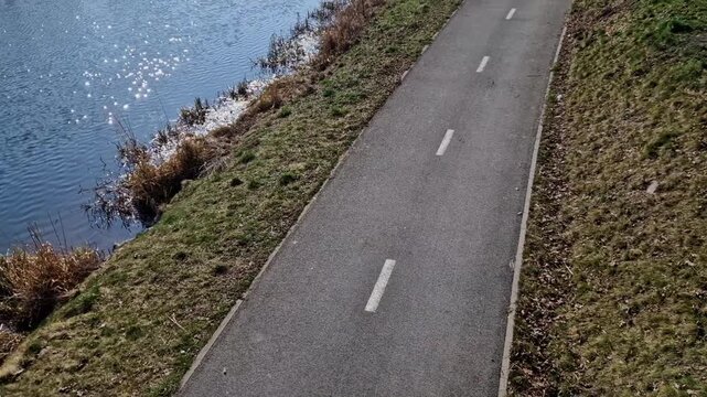  bike path right next to meanders encourages cyclists to continue along water, shared-use path or cycleway running alongside river or canal, given embankment.dashed white line indicates that path is i