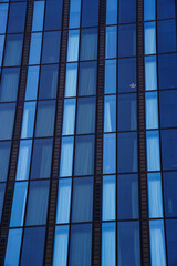 Obraz premium Close-up of a modern glass building facade in Vienna with repetitive window patterns, ideal as a clean architectural background for business, corporate, and technology concepts.