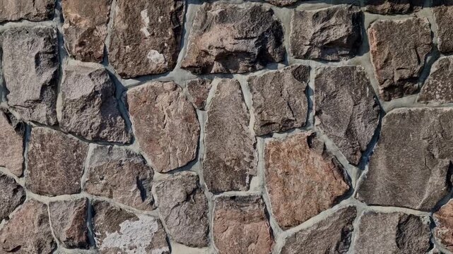 wall made of natural stone facade cladding or decorative element in interiors exteriors. durable type of stone marble gneiss sandstone, shades from gray brown and rusty stone chipped, rough surface ro