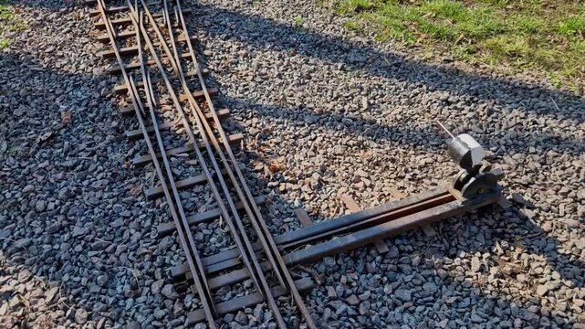 model railway switch located in the landscape. functional mechanical switch for garden railways or park tracks. sleepers and manual switch with signal for changing direction of travel.  switch is used