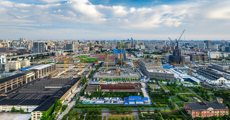 Fototapeta premium Aerial view of massive urban construction site with numerous cranes and industrial buildings against the Shanghai city skyline, China.