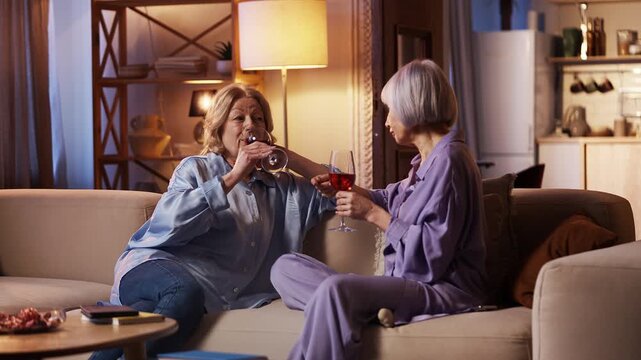 Happy women in their 60s sharing news over wine, warm trusting friendship